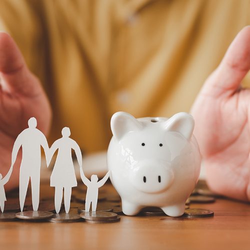 Businessman take a position to protect on the piggybank and paper family in hand, donation, saving, charity, family finance plan concept, fundraising, superannuation, financial crisis concept